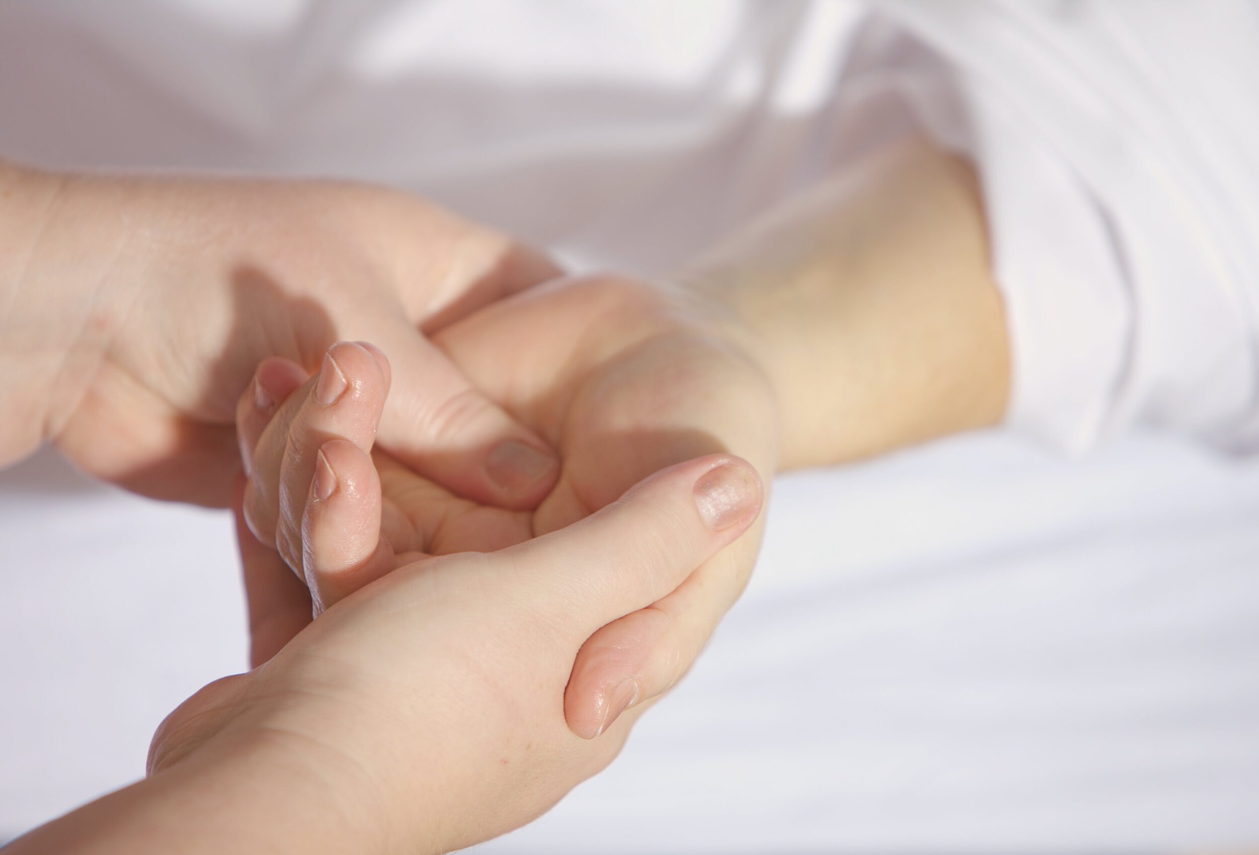 Eine Hand, die sich dem Sonnenlicht, was durch Baumkronen fällt, entgegen streckt.