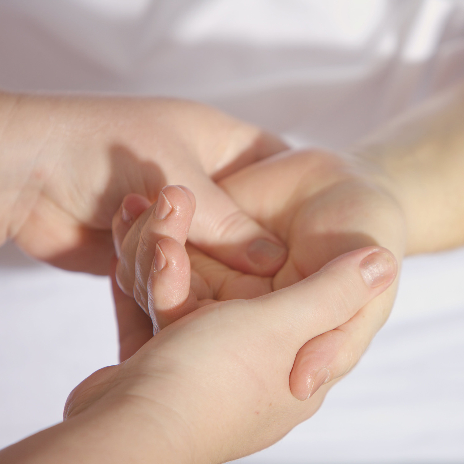 Zwei Hände massieren die Hand eines anderen Menschen